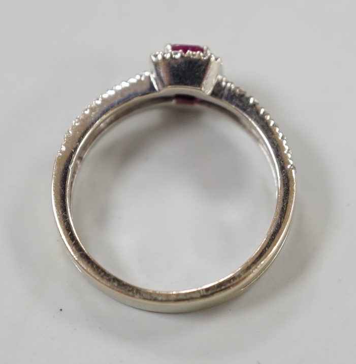 A modern 18ct white gold, single stone emerald cut ruby and diamond chip set cluster ring, with two row diamond chip set shoulders, size K, gross weight 3.3 grams.